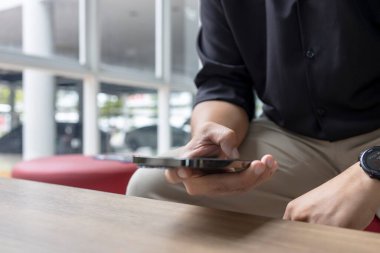 Modern kapalı alanda akıllı telefon kullanan bir adamın yakın çekimi. İş gündelik tarzı, rahatlatıcı, teknolojik yaşam tarzı, iletişim konsepti.