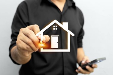Akıllı telefon ve kalem kullanan adam dijital akıllı ev arayüzü kullanıyor, emlak yönetimini, emlak teknolojisini ve modern ev yeniliklerini temsil ediyor..