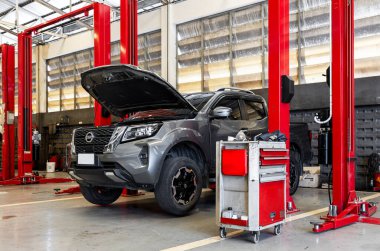  Servis kaputu açık, kırmızı hidrolik asansörlerle çevrili araba tamirhanesinde.