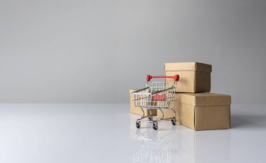 Küçük alışveriş arabası ve içinde dolar işaretleri olan kahverengi karton kutular, e-ticaret, satış, perakende ve çevrimiçi alışveriş konsepti