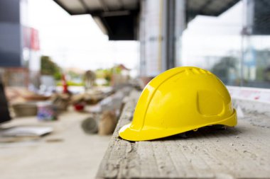 İnşaat alanında asılı duran sarı başlık, mühendisliği, kalifiye işçiliği ve endüstriyel güvenlik önlemlerini temsil ediyor.