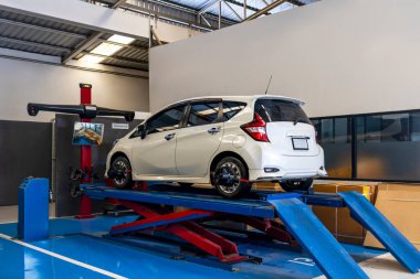 Profesyonel oto tamirhanesinde hidrolik asansörde tekerlek hizalama hizmeti veren modern bir araba.