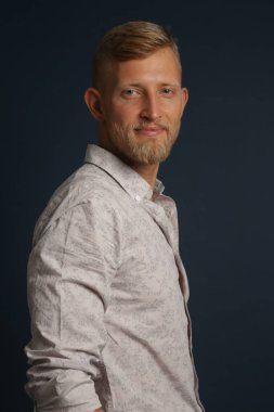 Kendine güvenen sarışın genç bir adam, stüdyo arka planında bir portre. İş, kanepe, ofis kavramı