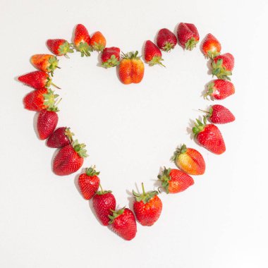 Beyaz arka planda kalp şeklinde taze çilekler.