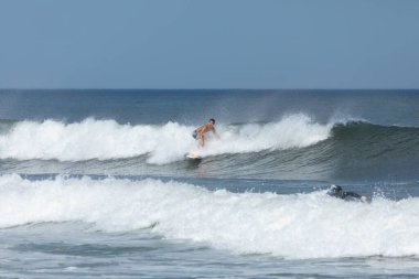 Deal, New Jersey - August 10, 2024: surfers surf the remnants of Hurricane Debby in the waters off Deal clipart