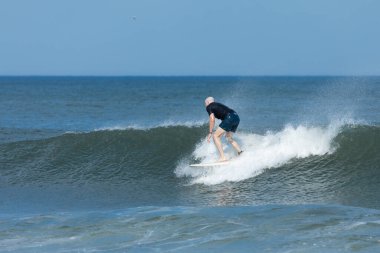 Deal, New Jersey - 10 Ağustos 2024: sörfçüler Debby Kasırgası 'nın kalıntılarında Deal açıklarında sörf yapıyor.