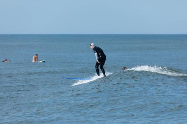 Deal, New Jersey - 10 Ağustos 2024: sörfçüler Debby Kasırgası 'nın kalıntılarında Deal açıklarında sörf yapıyor.