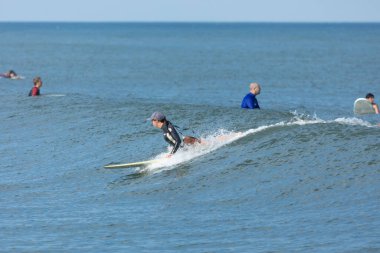 Deal, New Jersey - August 10, 2024: surfers surf the remnants of Hurricane Debby in the waters off Deal clipart