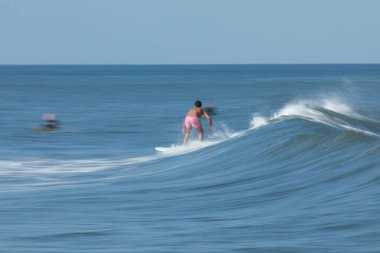 Deal, New Jersey - August 10, 2024: surfers surf the remnants of Hurricane Debby in the waters off Deal clipart