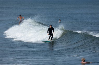 Deal, New Jersey - August 10, 2024: surfers surf the remnants of Hurricane Debby in the waters off Deal clipart