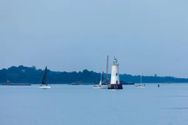 stock image South Amboy, New Jersey - August 14, 2024: Sailboats race near Great Beds Light on the Raritan Bay during golden hour