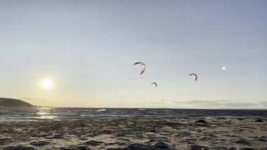 Uçurtmacılar Ağustos 2024 'te Sandy Hook' ta esinti ve sörften faydalanırlar.