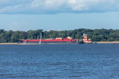 South Amboy, New Jersey - 21 Ağustos 2024: Güneşli bir yaz gününde yemyeşil bir hava ile çevrili New Jersey 'deki Arthur Kill' de bir römorkör yardımcı olur.