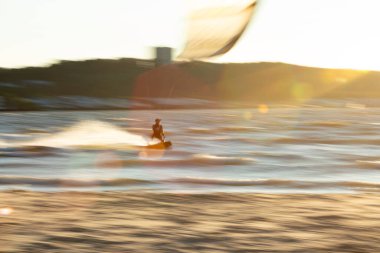 Sandy Hook, New Jersey - 21 Ağustos 2024: Kiteboardcular muhteşem bir yaz gecesinde Sandy Hook 'un üzerinde güneş batarken denize açılıyorlar. Hareket göstermek için kamera içinde bir çevirme tekniği kullanılır.