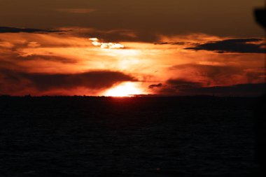 New Jersey 'deki körfezin üzerinde batan güneşin fotoğrafında gökyüzü yanıyor. Görüntü 21 Ağustos 2024 'te Sandy Hook' taki Hancock Kalesi 'nden alındı..