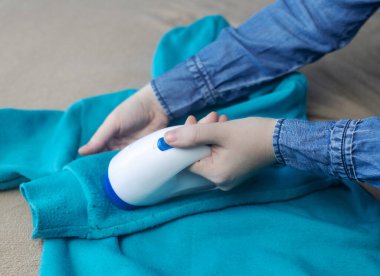 Peletleri çıkarmak için bir makine. Kız giysilerdeki ipliği çıkarmak için özel bir cihaz kullanıyor. Eski hasarlı giysilerin restorasyonu.