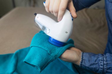 Peletleri çıkarmak için bir makine. Kız giysilerdeki ipliği çıkarmak için özel bir cihaz kullanıyor. Eski hasarlı giysilerin restorasyonu.