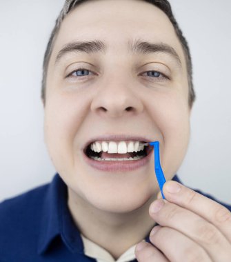 Interdental brush. A man shows a brush for cleaning the interdental space. Brush for cleaning teeth and daily oral care. Dentistry and orthodontics 