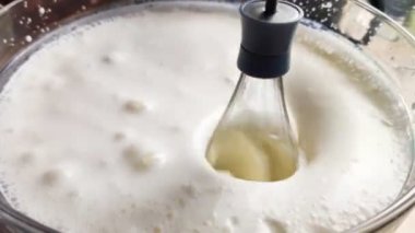 Bir tel, sütü kabın içinde çırpar. Krem şanti ve yumurta karışımı. Blender ameliyatından dolayı beyaz kabarcık sıvısı. Yakın çekim ve yavaş çekim efekti