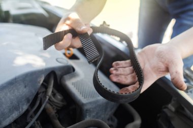 Zamanlama kayışı koptu. Kaputun yanındaki adam, motor çalışmadığı için bir arıza arıyor. Sürücü elinde kırık bir ön kemer tutuyor. Onarılamaz hasardan dolayı şok..
