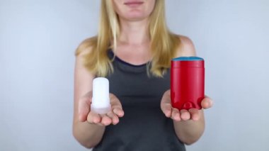 left or right. Girl chooses between eco-friendly deodorant without toxins and antiperspirant with toxic elements. In left hand Mineral alum crystal stick, in right hand classic remedy chemical nature