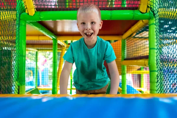 stock image Portrait of blond boy who plays in play area. Children labyrinth. Close-up of the face, on which emotions of happiness, fun and carelessness. Hill, labyrinth, trampoline. Safe attraction for children