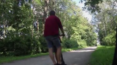 Bir baba oğluna elektrikli scooter sürmeyi öğretir. Koruyucu giysi olmadan e-scooter kullanmak. Pille çalışan araçlar kullanıldığında yaralanma riski artıyor. Araba kullanırken güvenliği sağlamada sorun kavramı