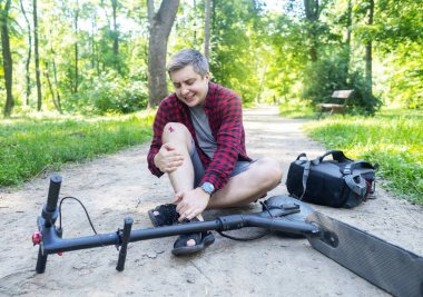 Adam elektrikli scooter sürerken düşmüş. Koruyucu giysi olmadan e-scooter kullanmak. Pille çalışan araçlar kullanıldığında yaralanma riski artıyor. Araba kullanırken güvenliği sağlamada sorun kavramı