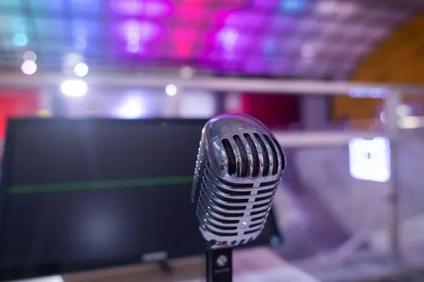 Microphone for karaoke. Close-up of a metal recording device against the backdrop of a studio or karaoke bar. Blurred background and emphasis on the device