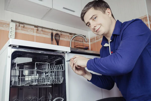 Dishwasher repair. A service center representative diagnoses and repairs a dishwashing machine at home. Specialist in working with home appliances. Call a technician to your home. Close-up