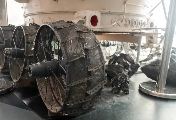 Mars rover. Imitation of a Mars rover wheel close-up. The stones imitate lunar soil. The axle, spokes, metal mesh frame, and base of the body are visible.