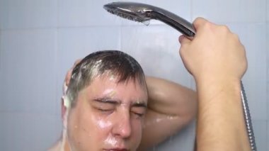 Adam kafa ovuyor. Koyu renk saçlı genç adam kepek, yağlı kafa derisi ve saç dökülmesi için kafa derisini yüzüyor. Cilt problemi saç problemlerine neden oluyor. Kendi kendine masaj ve saç teline sürtünme..