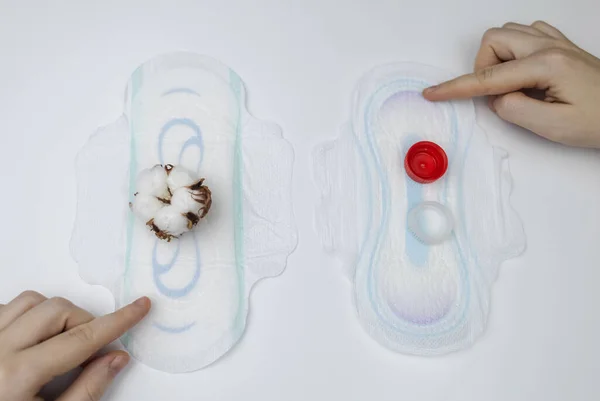 Sanitary napkin and cotton plant flower. A concept that shows the presence of plastic additives in sanitary pac, which cause redness, rash, and diaper rash in the female genital organs.