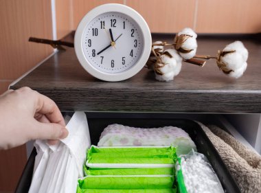 Hijyenik peçete, tampon ve pamuk çiçeği. Kadınlar regl olmak için içinde hijyen ürünleri olan çekmeceyi açarlar. Pamuk çiçeği plastiğin yokluğunu sembolize eder. Çevresel malzemelerden yapıldı