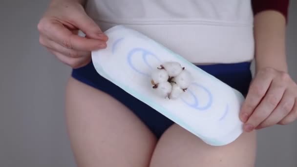 サニタリーナプキンと綿花 女の子は彼女のパンティの背景に対して綿の衛生パッドを示しています 女性月経のためのプラスチックフリー製品の概念 エコフレンドリーな製品 — ストック動画