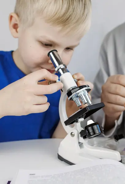 Child chemist. Teacher shows a visual experiment. A science mentor teaches an experimental approach. Microscope, petri dish, pipettes, books. Practical work in chemistry or physics. Laboratory work