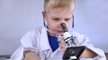 Çocuk kimyageri. Öğretmen görsel bir deney gösteriyor. Bir bilim danışmanı deneysel bir yaklaşım öğretir. Mikroskop, petri kabı, pipetler, kitaplar. Kimya veya fizik alanında pratik bir çalışma. Laboratuvar çalışması