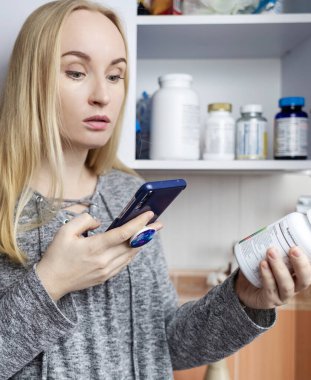 Kız, beslenme takviyeleri üzerine çalışıyor. Bir şişe vitamin kompleksinin talimatlarını okuyorum. Saç dökülmesi ve bağışıklığın zayıflaması için besin takviyesi. Reçetesiz ilaç kullanımı ve sağlığa zarar