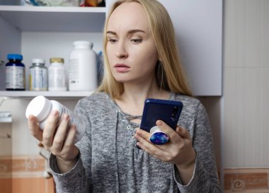Kız, beslenme takviyeleri üzerine çalışıyor. Bir şişe vitamin kompleksinin talimatlarını okuyorum. Saç dökülmesi ve bağışıklığın zayıflaması için besin takviyesi. Reçetesiz ilaç kullanımı ve sağlığa zarar