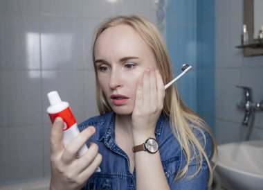 Toothpaste ingredients. Girl checks composition of toothpaste and is surprised by dangerous composition of product. Emulsifiers, preservatives, dyes, PEG, SLS, parabens, diethanolamine clipart