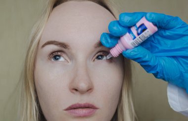 Mantarların ve genişlemiş göz bebeklerinin muayenesi. Bir doktor midriazi ve konaklama spazmı olan bir kadına göz muayenesi yapar. Zayıf görme ve göz kaslarında felç