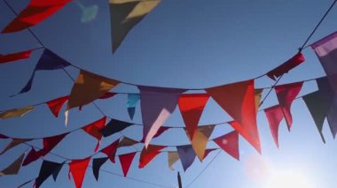 Karnavalın parkında asılı bir çelenk. Bayram ve parti için çok renkli süslemeler. Mavi gökyüzünün arka planına karşı güneş ışınlarıyla aydınlatılmış.