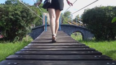 İp köprüsü. Genç bir kadın lunaparktaki asma köprüden yavaşça geçiyor. Bacaklarını kapat..