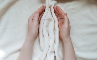 Female hands hugging folds of soft tissue in the shape of the labia, vagina and vulva. The concept of women's intimate health, prevention of gynecological diseases