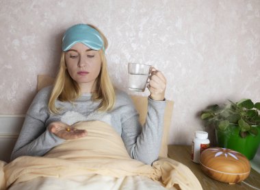 Bir kadın uyuyamaz ve bir kapsül melatoninle uyku hapı içmek ister. Jitlag veya uykusuzluk belirtileri. Biyolojik ritimlerin düzenlenmesi
