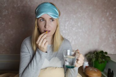 Bir kadın uyuyamaz ve bir kapsül melatoninle uyku hapı içmek ister. Jitlag veya uykusuzluk belirtileri. Biyolojik ritimlerin düzenlenmesi