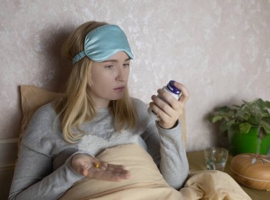 Bir kadın uyuyamaz ve bir kapsül melatoninle uyku hapı içmek ister. Jitlag veya uykusuzluk belirtileri. Biyolojik ritimlerin düzenlenmesi