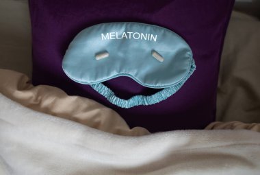 Bir kadın uyuyamaz ve bir kapsül melatoninle uyku hapı içmek ister. Jitlag veya uykusuzluk belirtileri. Biyolojik ritimlerin düzenlenmesi