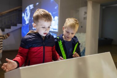 Children read about the mammoth in the natural history museum. In the foreground is the skeleton of an extinct species of mammal of the genus Mammuthus clipart