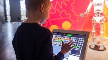 Çocuklar bilim fuarında bir robotu tablet bilgisayar kullanarak kontrol ediyorlar. Modern teknolojiler ve çocukların bilimsel eğitimi